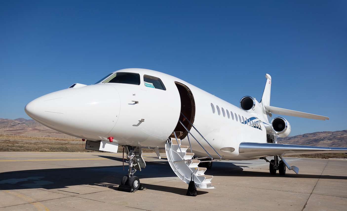 White private jet with boarding stairs on tarmac